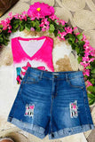Pink tie-dye top and blue denim shorts with floral designs on a woven surface with pink flowers.