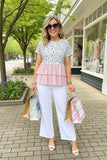 Woman in a layered outfit with a leopard print top and pink ruffled layer, white pants, and sunglasses, standing on a sidewalk with shopping bags.