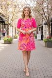 Woman in a colorful dress standing on a street with cherry blossom trees in the background